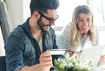 Couple at a laptop with a debit card