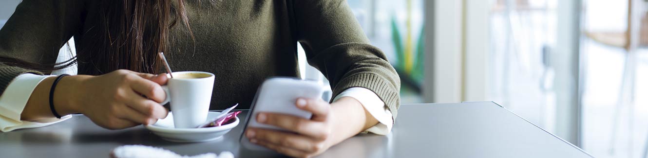 Lady at a coffee shop on smartphone.